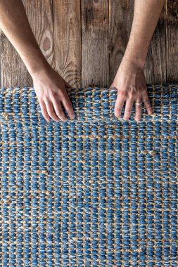 Odada yerde yuvarlanan bir adam, üst manzara, parça parça renkli halı, parlak hasır mavisi halı.