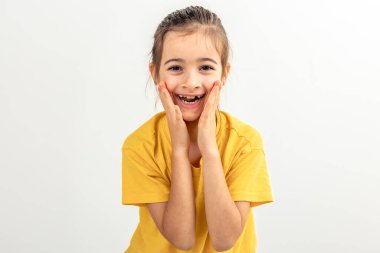 Beyaz arka planda küçük beyaz bir kız komik suratlar yapıyor, izole edilmiş, kopyalama alanı.