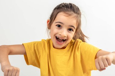 Sarı tişörtlü, beyaz arka planda izole edilmiş görünmez bir araba kullanan komik beyaz kız..