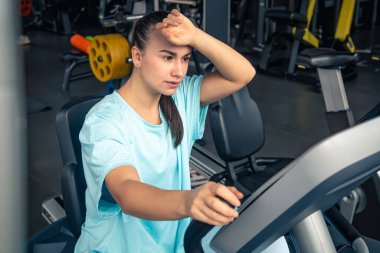 Bisikletli yorgun bir kadın spor salonunda kardiyo antrenmanı yapıyor genç bir kadın spor salonunda egzersiz yapıyor..