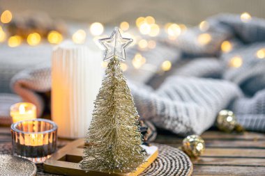 Dekoratif küçük bir köknar ağacıyla Noel kompozisyonu bulanık bir zemin üzerinde örülmüş element ve bokeh ışıkları ile, boşluğu kopyala.