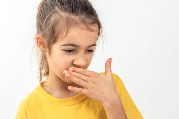 Little school girl kid feeling bad and dislike smell, dressed in yellow t-shirt, isolated on white background, copy space.