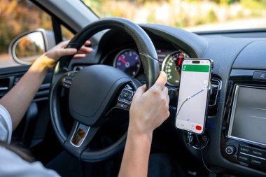 Cep telefonunda navigasyon ya da GPS kullanan bir kadın, bir yolculuk sırasında akıllı telefondan bir konum haritasını çevrimiçi görüyor.