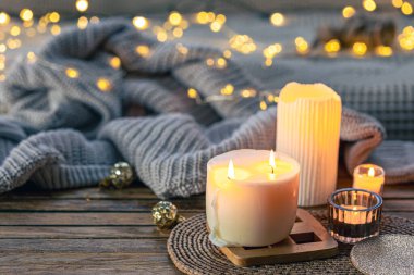 Örülmüş bir element ve çelengin bulanık arka planında yanan mumlarla dolu rahat bir hayat, boşluğu kopyala.