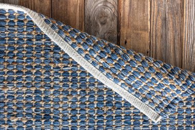 Ahşap zeminde el yapımı geometrik kot halısı, parlak hasır renkli halı..