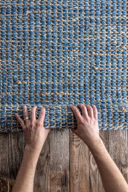 Odada yerde yuvarlanan bir adam, üst manzara, parça parça renkli halı, parlak hasır mavisi halı.