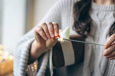 Hediye kutusunu tutan kadın elinde bir maytapla ateş yakıyor, kapanış, Noel kutlaması konsepti, kopyalama alanı.