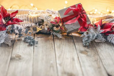 Ahşap bir yüzeyde dekoratif detaylarla dolu samimi bir Noel arkaplanı. Dekoratif çiçekler ve tahta bir masada hediye kutuları. Kış afişi tasarımı.
