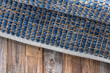 Ahşap zeminde el yapımı geometrik kot halısı, parlak hasır renkli halı..