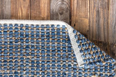 Ahşap zeminde el yapımı geometrik kot halısı, parlak hasır renkli halı..