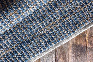 Ahşap zeminde el yapımı geometrik kot halısı, parça renkli halı, parlak hasır renkli halı..