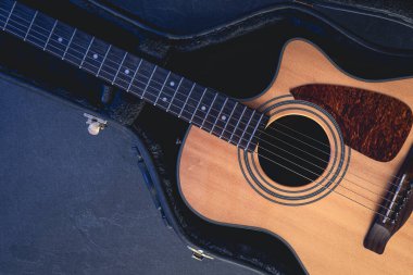 Koruyucu bir çantadaki akustik gitar. Arka planda, üst tarafta, müzikal arka planda..