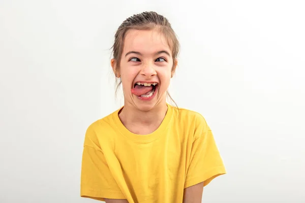 Kleines Kaukasisches Mädchen Gelbem Shirt Macht Lustige Gesichter Auf Weißem lizenzfreie Stockbilder