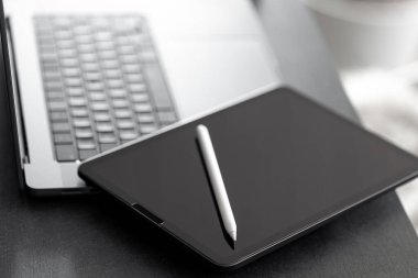 Dijital tablet, stilus kalem ve dizüstü bilgisayar evdeki ofis masasında, kapat, siyah ve beyaz.