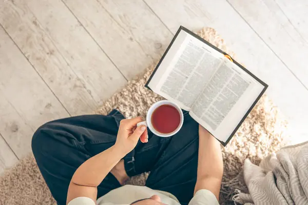 Draufsicht Frau Hält Tasse Tee Während Sie Ein Buch Auf Stockbild