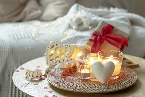 Romantic composition for Valentines Day with candles and decorative hearts in the interior of the room. Copy space.
