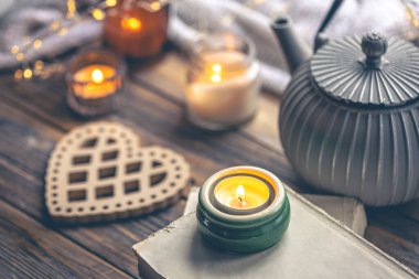 Sıcak ev kompozisyonu, yanan mumlar, kitaplar ve çay. Boşluğu kopyala.