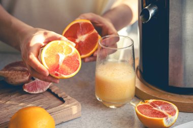 Ev mutfağında portakal suyu yapma süreci. Bir kadın evde elektrikli meyve sıkacağıyla portakal suyu yapıyor. Elektrikli meyve sıkacağı kullanarak taze portakal suyu hazırlıyorum..