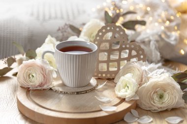 Sevgililer Günü için sıcak ev kompozisyonu çiçekler, bir fincan çay ve dekoratif kalp. Boşluğu kopyala.