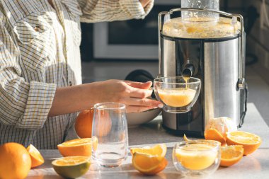 Bir kadın evde elektrikli meyve sıkacağıyla portakal suyu yapıyor. Evde taze sıkılmış portakal suyu yapıyorum..