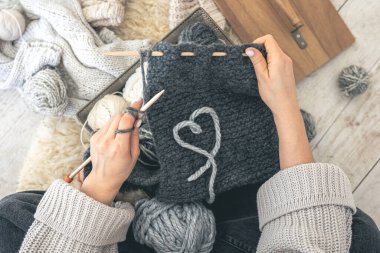 Gri iplikli ve örgü örgülü bir kadın yerde oturuyor. El yapımı giysiler. Kız hobileri için içeri giriyor. Örgü konseptine bayılırım..