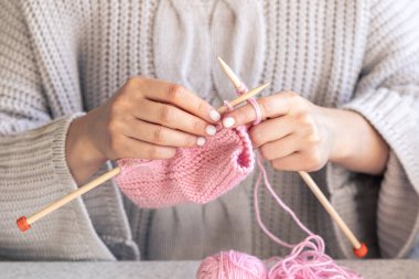 Pembe yün kazak ören kadın ellerinin yakın çekimi. Kız hobileri için içeri giriyor. Örgü konsepti.