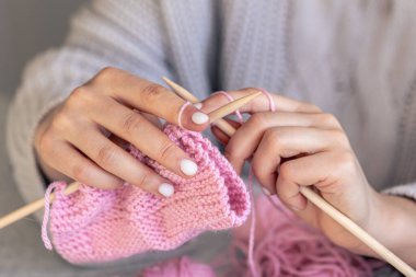 Pembe yün kazak ören kadın ellerinin yakın çekimi. Kız hobileri için içeri giriyor. Örgü konsepti.