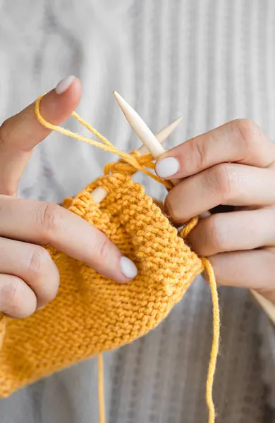 Sarı yün kazak ören kadın ellerinin yakın çekimi. Kız hobileri için içeri giriyor. Örgü konsepti.