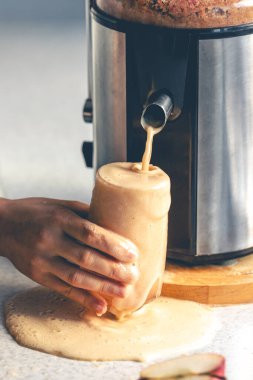 Bir kadın evde meyve sıkacağıyla elma suyu yapıyor. Kadın mutfakta sağlıklı meyve suyu hazırlıyor. Meyve suyu ve meyve suyu..