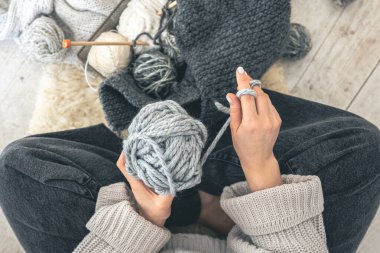 Gri iplikli ve örgü örgülü bir kadın yerde oturuyor. El yapımı giysiler. Kız hobileri için içeri giriyor. Örgü konseptine bayılırım..