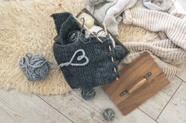 Sıcak gri örgü elementi, iplik ipliğinden yapılmış bir kalp ve üst görünümü olan rahat bir kompozisyon. Örgü konsepti.