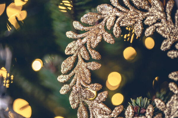 Christmas background with a golden decorative wreath on a Christmas tree branch with a garland.