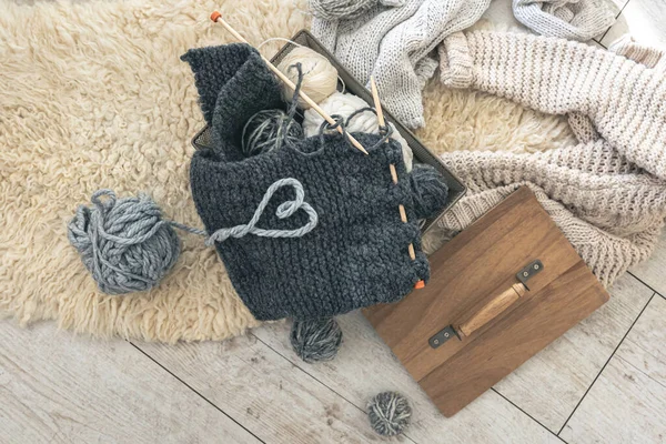 Sıcak gri örgü elementi, iplik ipliğinden yapılmış bir kalp ve üst görünümü olan rahat bir kompozisyon. Örgü konsepti.