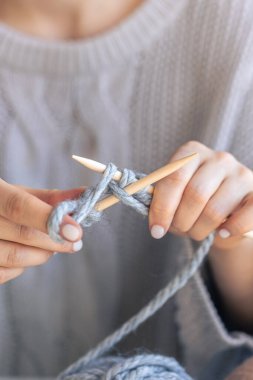Dairesel iğneler kullanarak örgü ören ellerin yakın çekimi. Kadın kalın iplikten örgü örüyor. El yapımı giysiler. Kız hobileri için içeri giriyor..