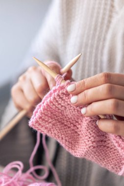 Pembe yün kazak ören kadın ellerinin yakın çekimi. Kız hobileri için içeri giriyor. Örgü konsepti.