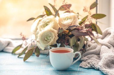 Bir fincan çay, çiçekler ve örgü elementli kompozisyon. Boşluğu kopyala.