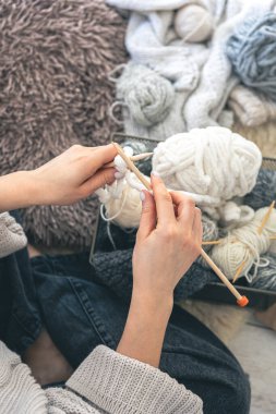 Genç bir kadın evde kalın bir kazak örüyor. Manzaralı. Kız hobileri için içeri giriyor. Örgü konsepti. Boşluğu kopyala.