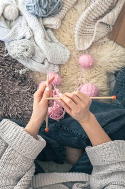 Kadın elleri evde sıcak pembe eşarp örer, üst manzara. El yapımı giysiler. Kız hobileri için içeri giriyor. Örgü konsepti.