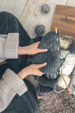 Gri yün kazak ören kadın ellerinin yakın çekimi. Kadın kalın iplikten örgü örüyor. El yapımı giysiler. Kız hobileri için içeri giriyor..