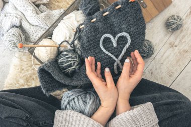 Gri iplikli ve örgü örgülü bir kadın yerde oturuyor. El yapımı giysiler. Kız hobileri için içeri giriyor. Örgü konseptine bayılırım..