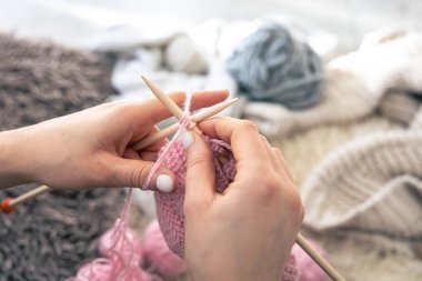 Dairesel iğneler kullanarak örgü ören ellerin yakın çekimi. Kız hobileri için içeri giriyor. Örgü konsepti.