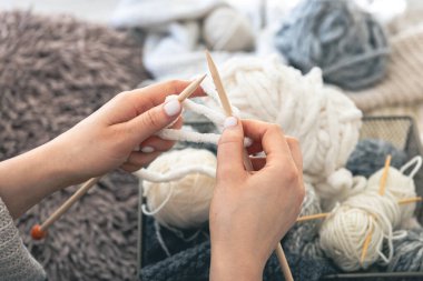 Genç bir kadın evde kalın bir kazak örüyor. Manzaralı. Kız hobileri için içeri giriyor. Örgü konsepti. Boşluğu kopyala.