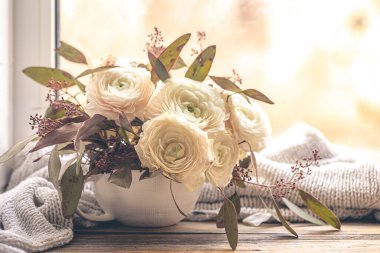 Pencerenin yanında bir buket ranunculus çiçeğiyle bahar arkaplanı.