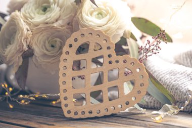 Yakın plan, dekoratif ahşap kalp ve ranunculus çiçekleri. Sevgililer Günü için şenlik arka planı.