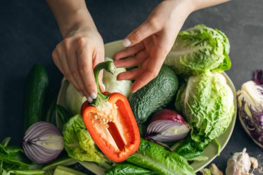 Bir kadının ellerinde taze sebzelerin arka planına karşı dolmalık biber. Sağlıklı yeme kavramı.