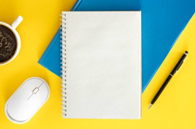 Ofis arkaplan tasarımı, boş not defteriyle düz uzanma, sarı arka planda bir fincan kahve ve bilgisayar faresi, üst görünüm.