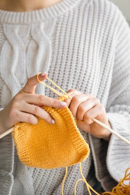 Sarı yün kazak ören kadın ellerinin yakın çekimi. Kız hobileri için içeri giriyor. Örgü konsepti.