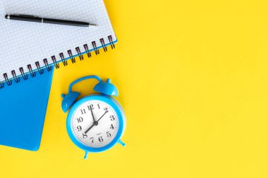 Sarı arkaplanda notlar ve mavi alarm saati, üst görünümde, boşluğu kopyala.