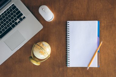 Üst düzey ahşap ofis masası, dizüstü bilgisayarı, boş not defteri ve küresi, kopyalama alanı. Okul ve eğitim kavramı.