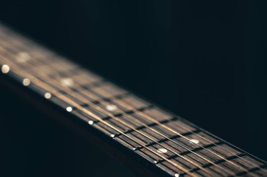 Kapat, akustik gitardaki dizgiler bulanık siyah arkaplan kopyalama alanı üzerinde.